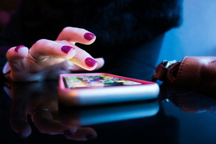orang yang menggunakan smartphone hitam dengan casing abu-abu dan merah muda