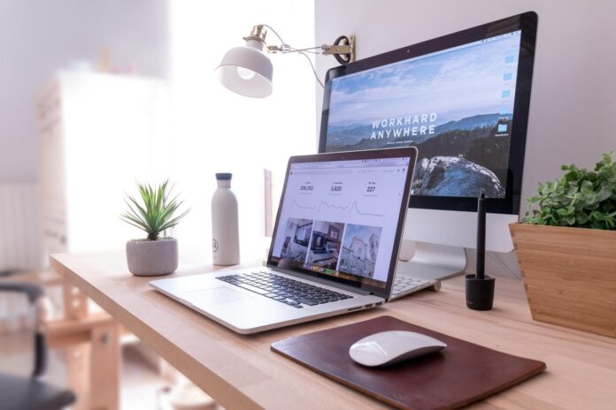 MacBook Pro di atas meja di samping iMac putih dan Magic Mouse