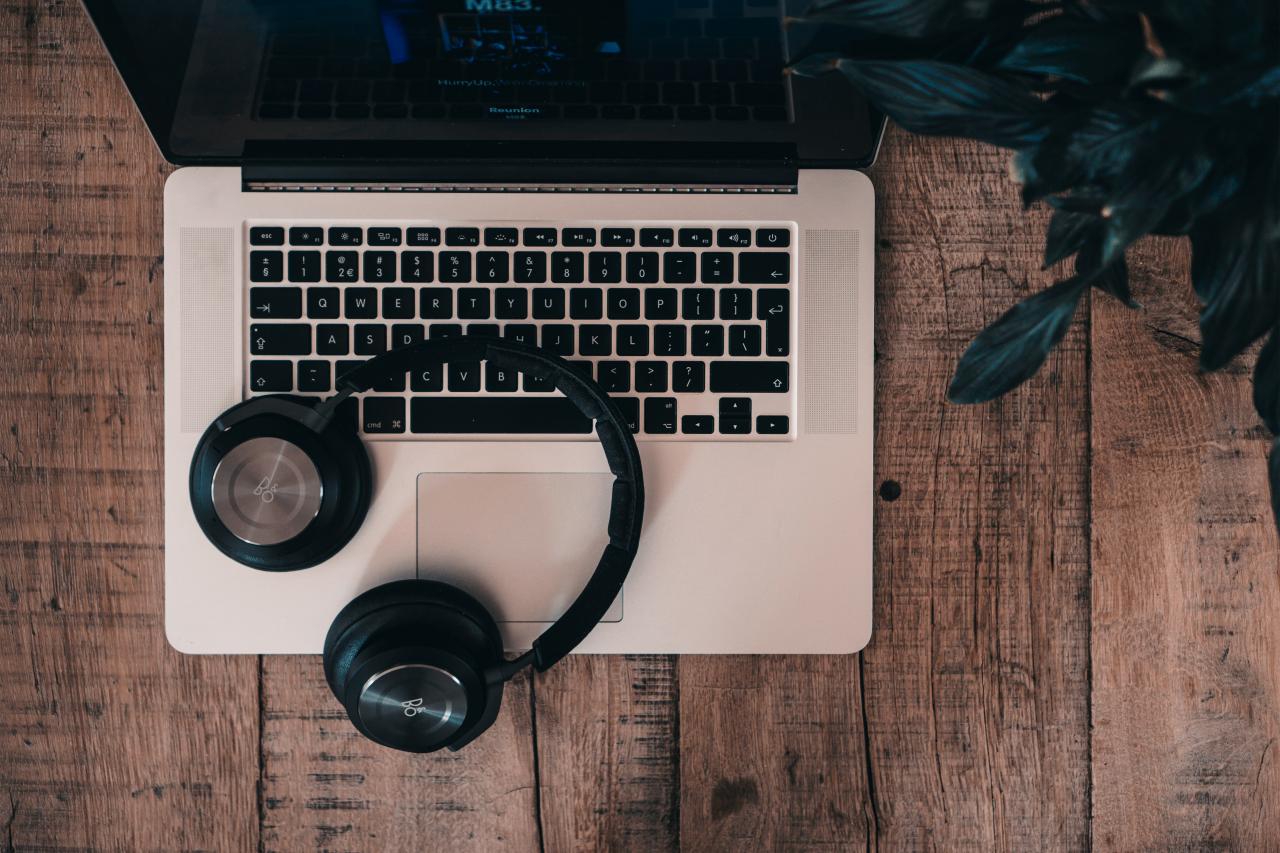 headphone Bluetooth nirkabel hitam di atas MacBook Pro